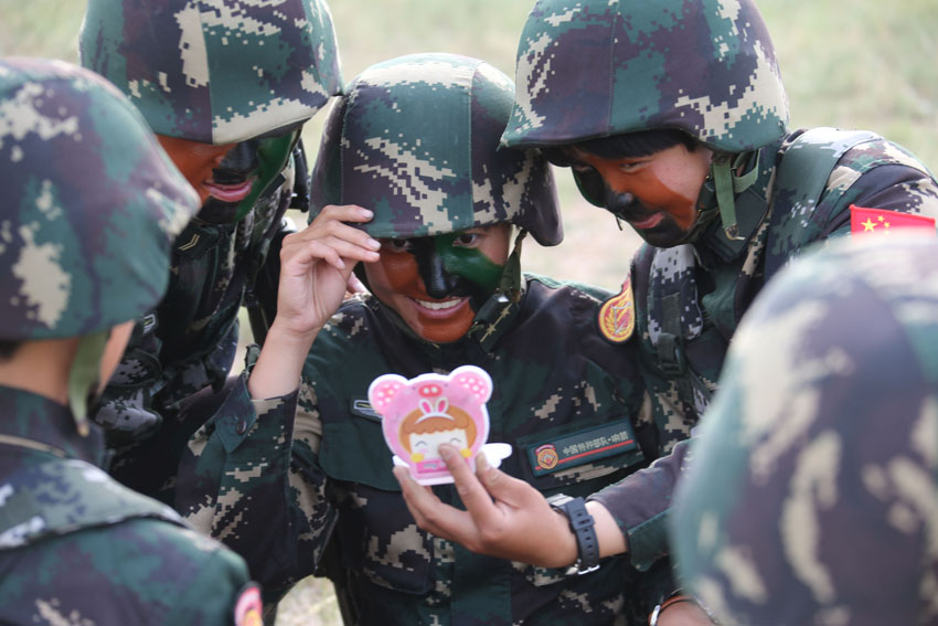 在朱日和训练基地，女子特战连官兵对镜查看迷彩伪装（7月17日摄）。