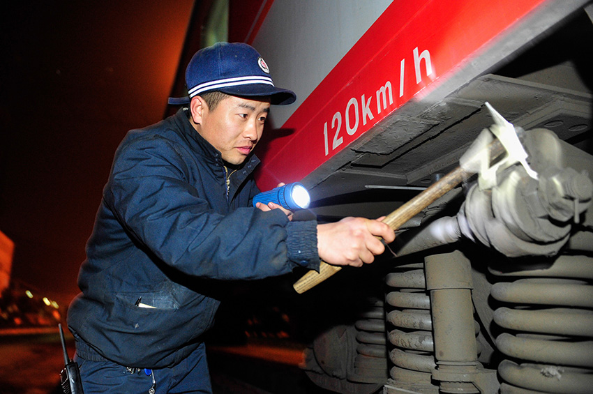 1月21日,成都铁路局贵阳车辆段的工作人员在夜幕中检修列车.
