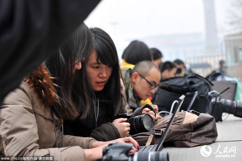2014年两会：美女记者席地而坐发稿忙,天安门广场成新闻中心。 东方IC 
