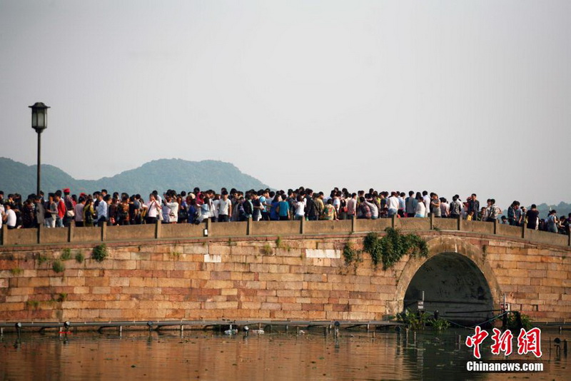5月1日，五一小长假首日，杭州西湖景区迎来八方宾客。断桥景点，游人比肩接踵，只见人头不见桥头。中新社发 李晨韵 摄