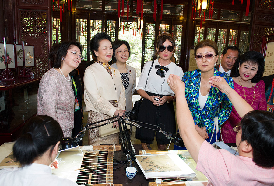 彭丽媛和来宾欣赏顾绣传承人苏惠萍用细若游丝的线一次成功穿过针眼。新华社记者黄敬文摄