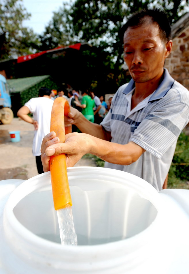 8月4日，河南郏县曹沟村村民李何龙从送水车上取水。