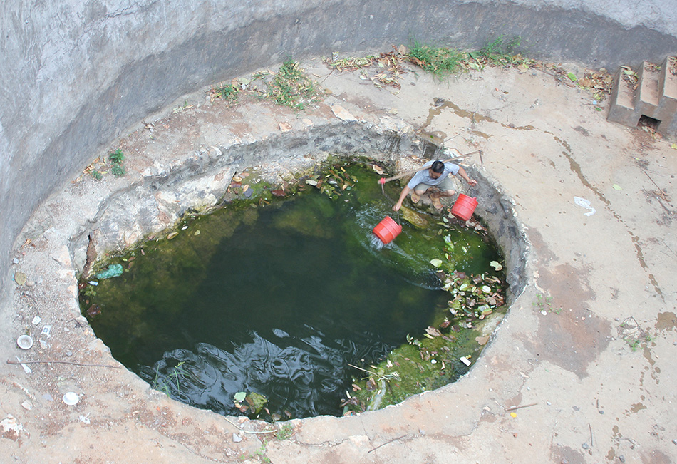 8月6日，湖北省十堰市郧县谭山镇严家岭村村民在水位严重下降的蓄水池中取水。