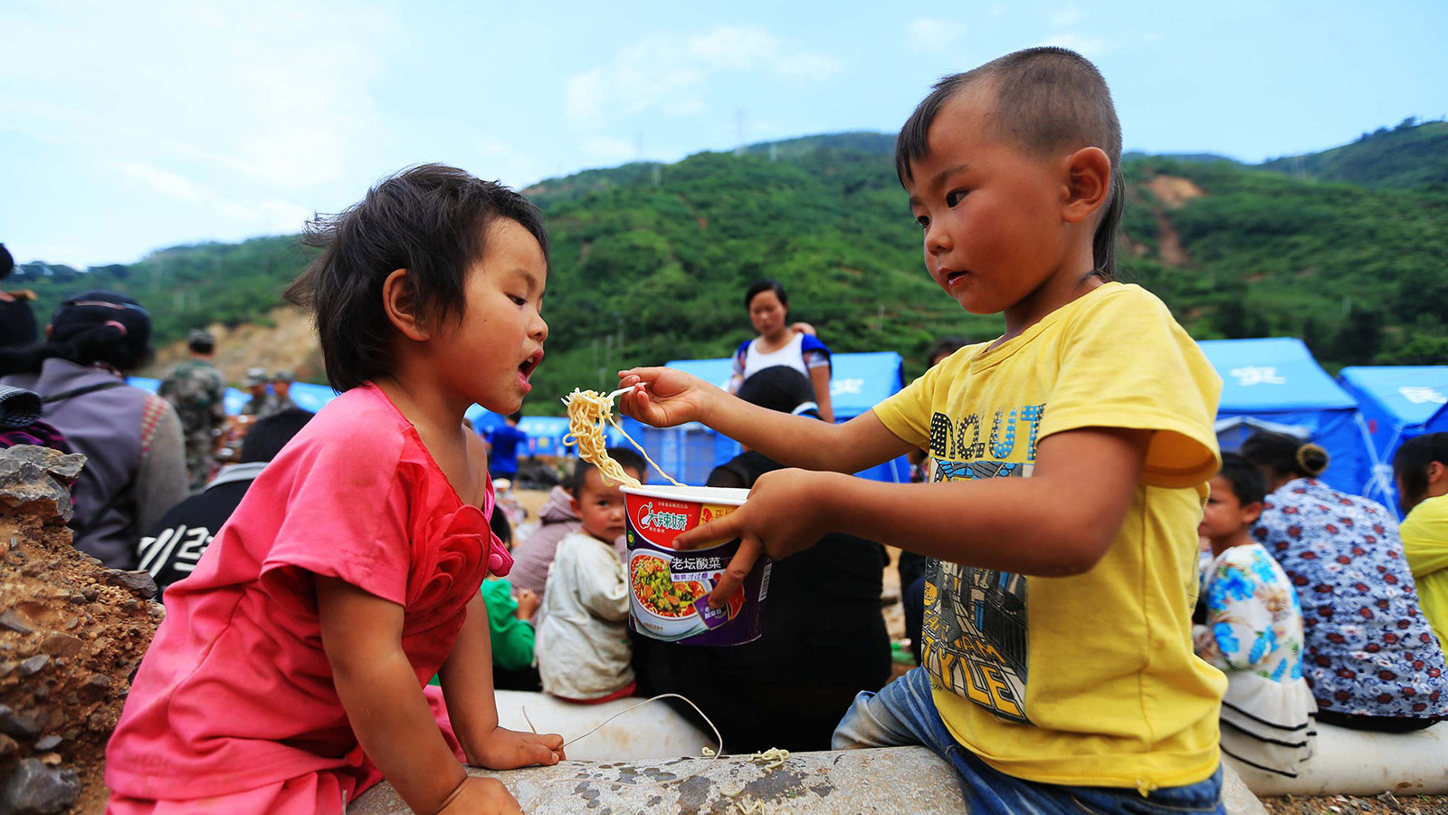 8月5日，云南省昭通市鲁甸县龙头山镇四岁的小男孩熊鑫（右）在喂邻居家的小女孩吃方便面。新华社记者邢广利摄