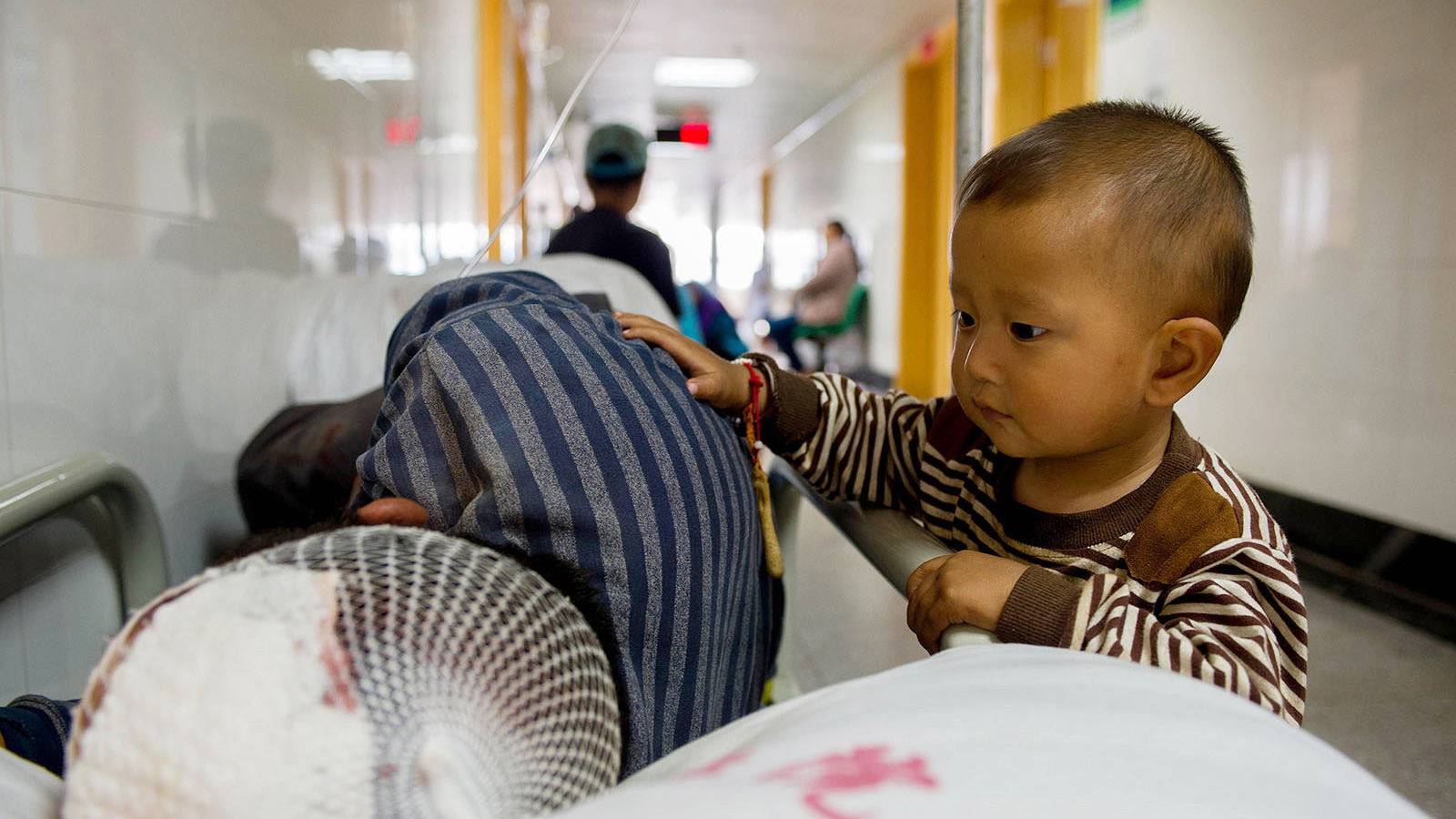 8月5日，在鲁甸县人民医院，一名孩子陪在受伤的爷爷身旁。新华社记者胡超摄