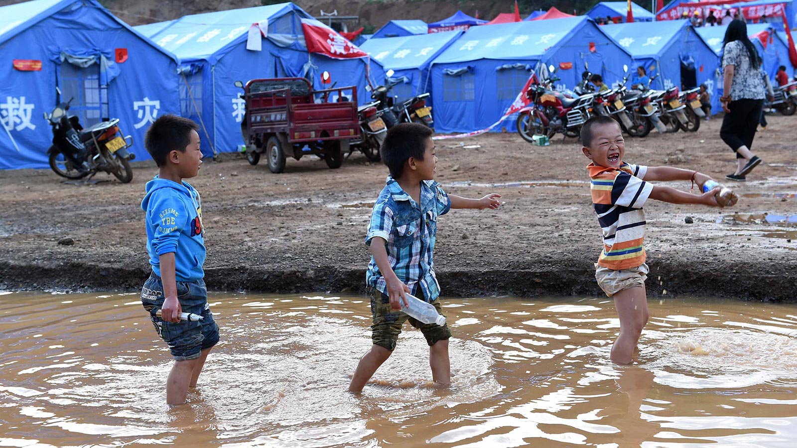 一些孩子在云南鲁甸县龙头山镇的临时安置点外的小河里玩耍（8月6日摄）。新华社记者蔺以光摄
