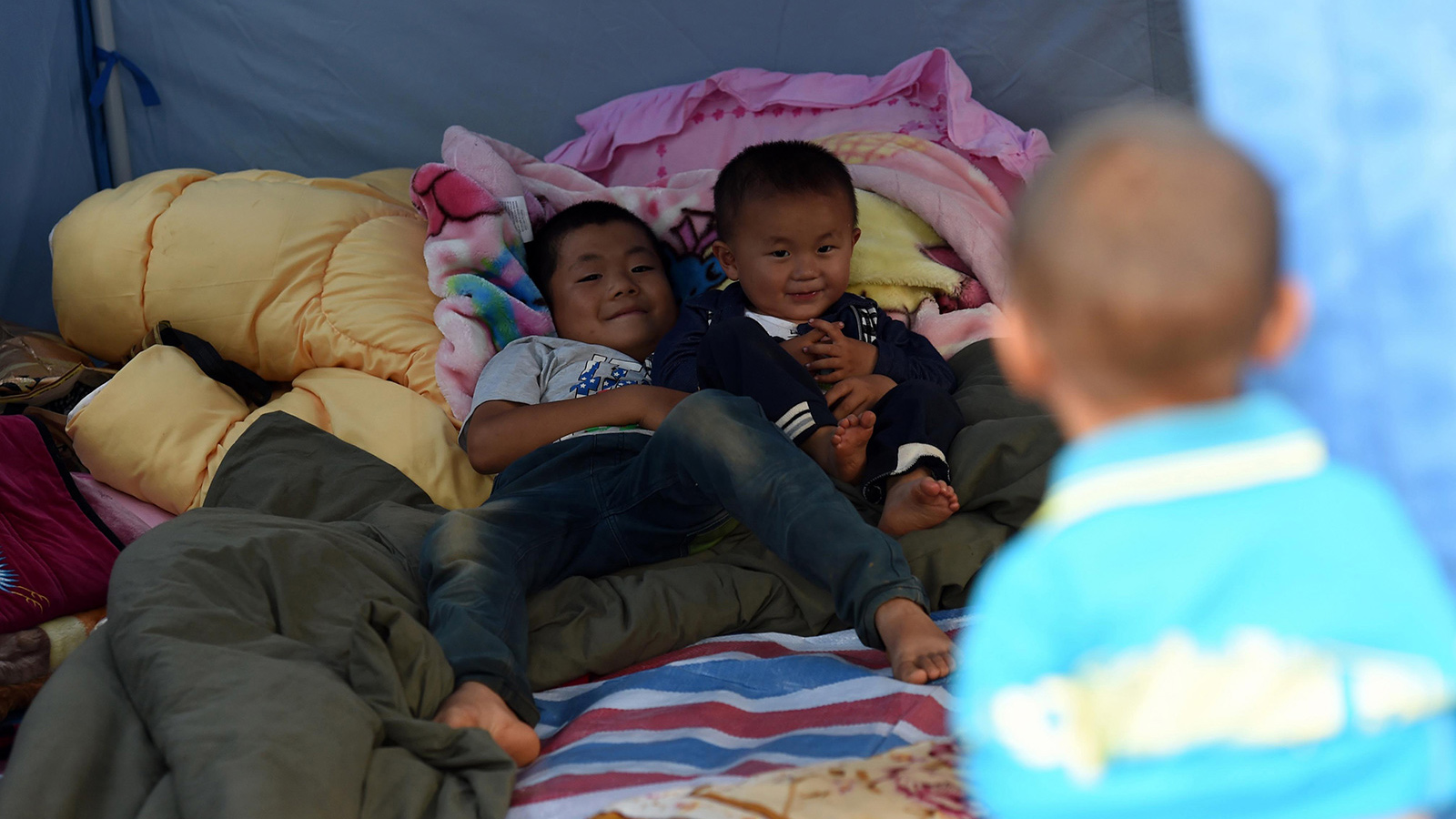 几名小男孩在云南鲁甸县龙头山镇的临时安置点的帐篷内玩耍（8月6日摄）。新华社记者蔺以光摄