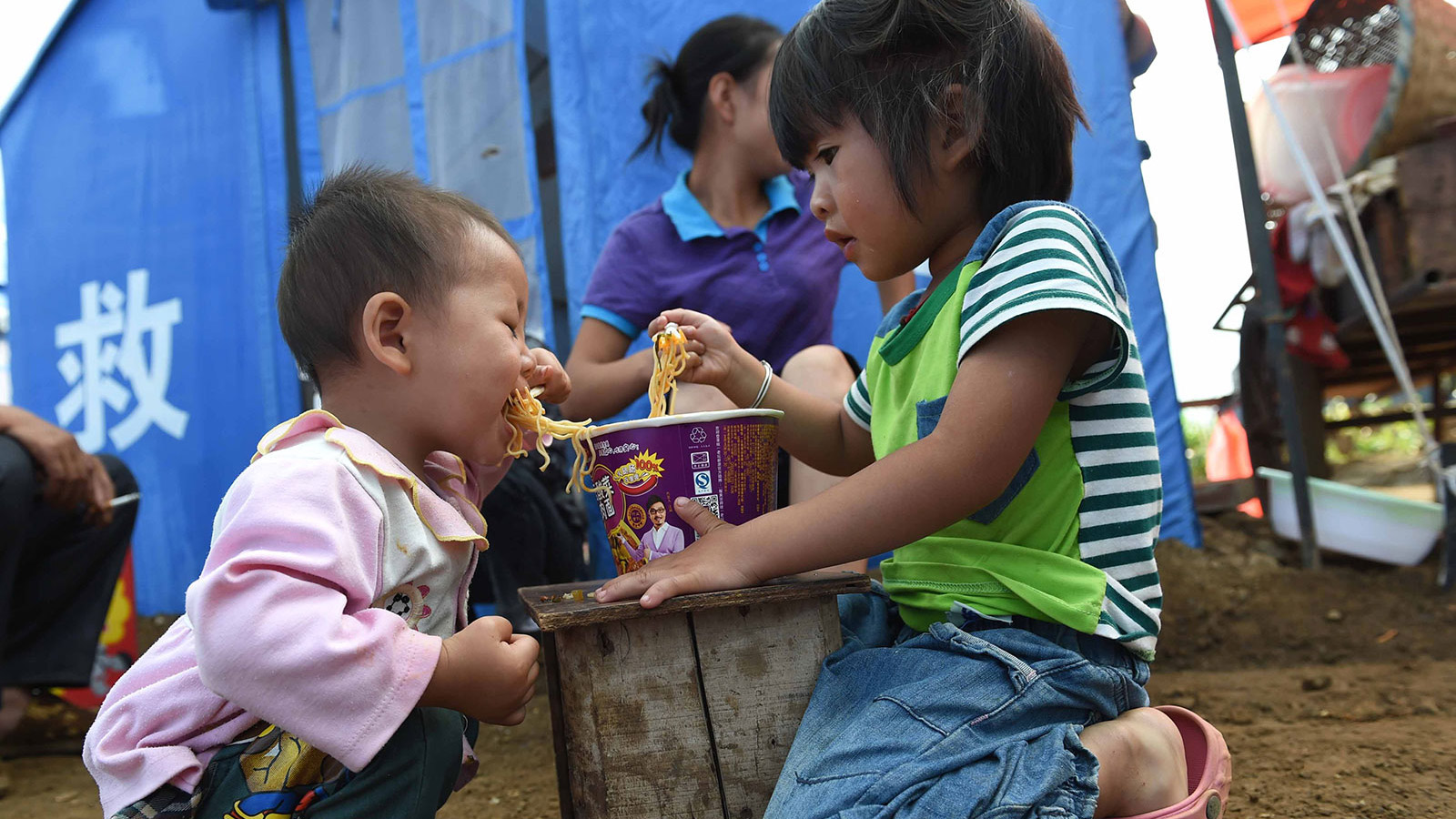 8月7日，5岁的谢维佳（右）和妹妹在云南鲁甸县龙头山镇的临时安置点吃早餐。新华社记者蔺以光摄