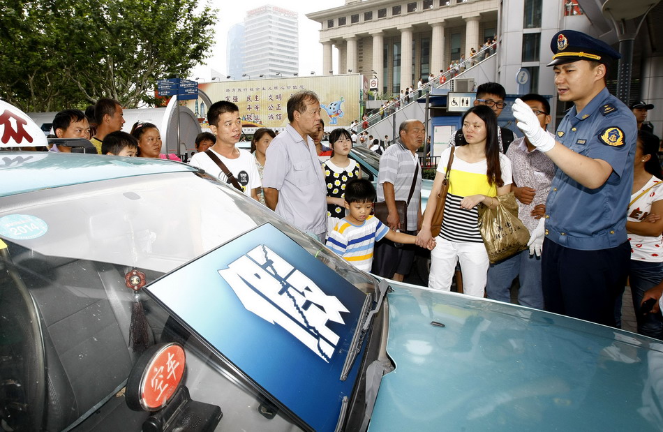 8月10日，在上海陆家嘴地铁广场，交通执法人员向市民讲解辨别真假出租车的方法。
