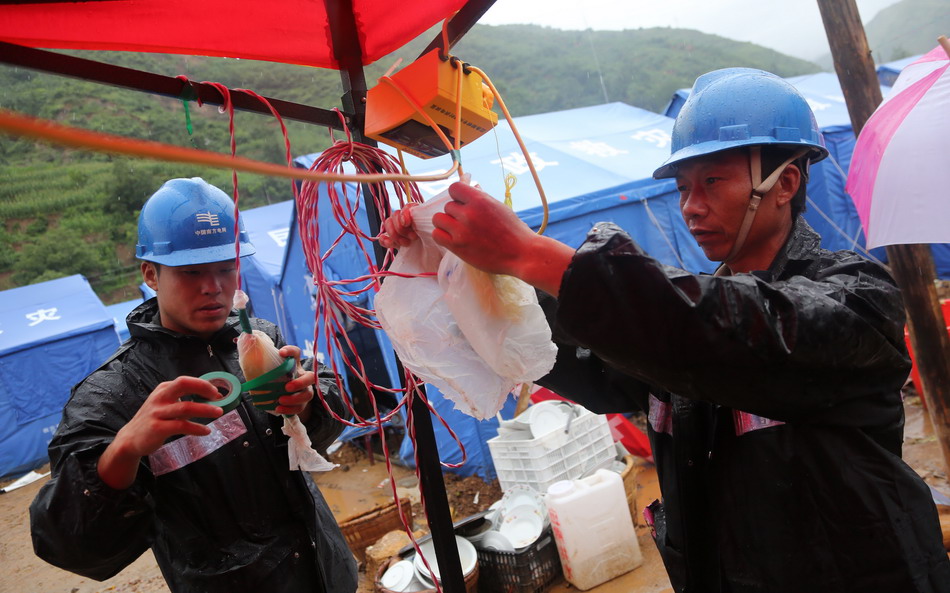 8月11日，在鲁甸县龙头山镇，电力部门的工作人员在安置点内为裸露的电线插座包上塑料袋防水。