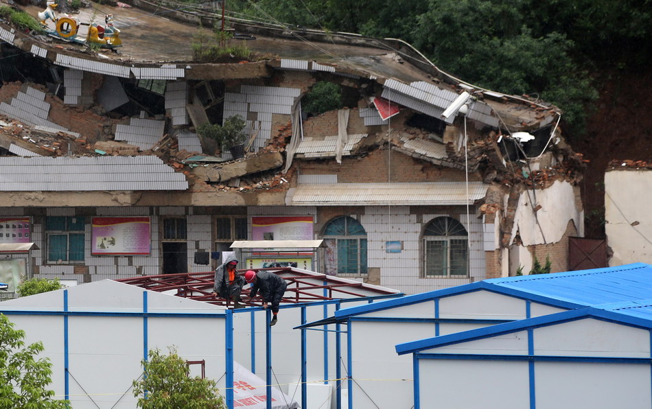 8月11日，在鲁甸县龙头山镇，两名工人在安置点冒雨搭建震区第一所板房希望小学。