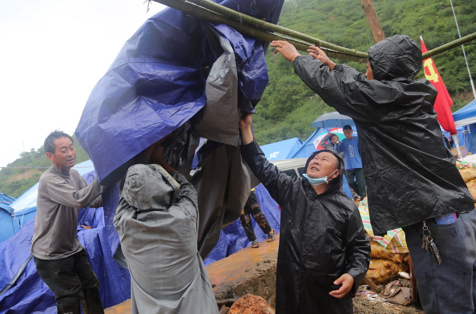 8月11日，在鲁甸县龙头山镇，受灾群众在安置点内给大锅饭厨房搭帐篷防雨。