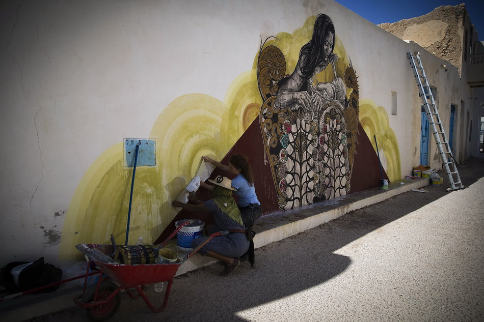  8月7日，在突尼斯杰尔巴岛，美国艺术家莫妮卡・卡尼劳（左）和同伴在创作壁画。