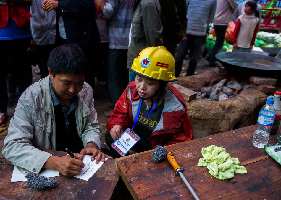  8月12日，在龙头山镇营盘村，公益人孙丽（右）与村干部登记救援物资数量。