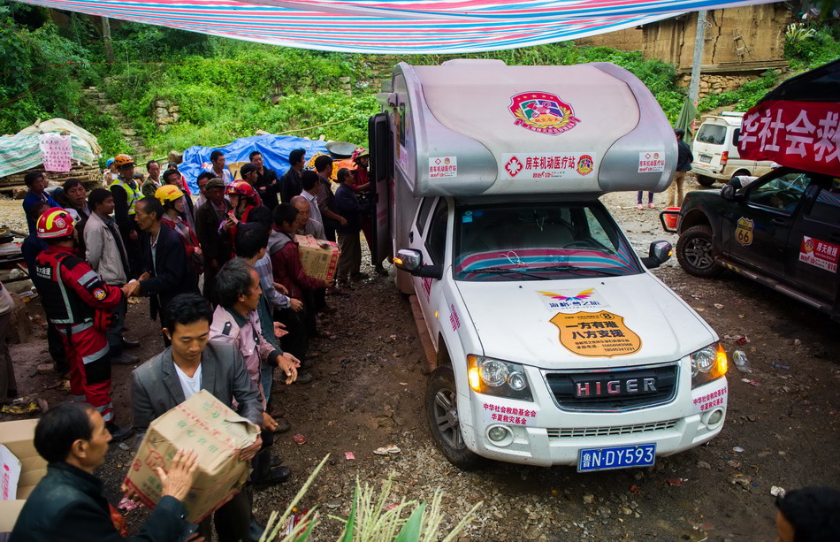 8月12日，龙头山镇营盘村，受灾群众从房车上卸载救援物资。