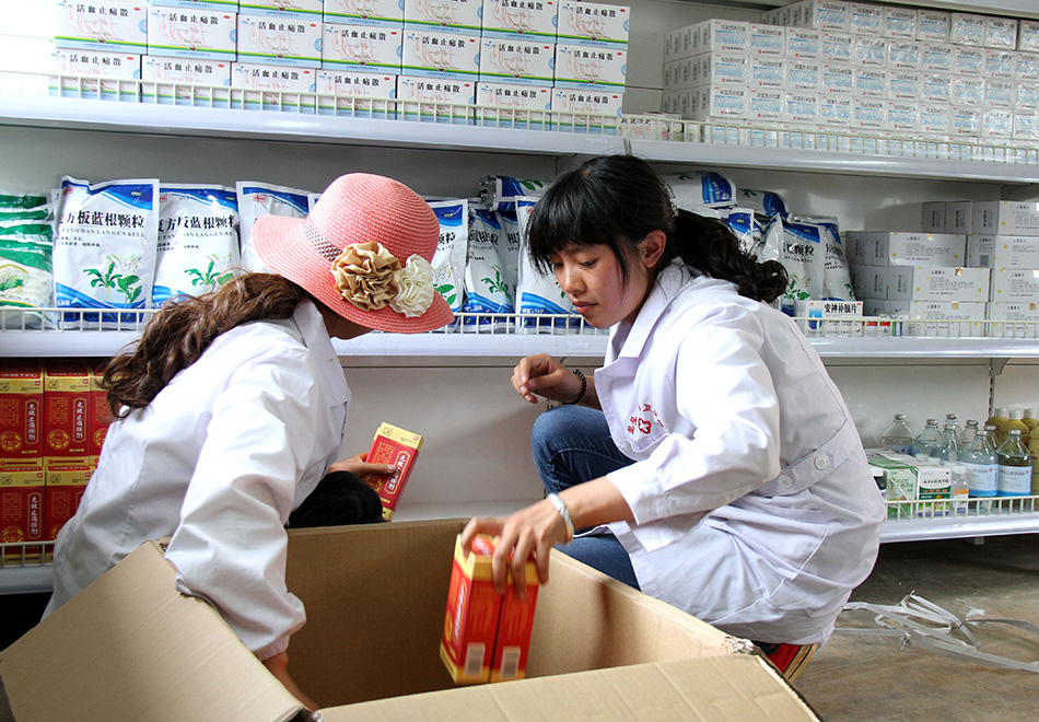 8月13日，龙头山镇中心卫生院的两名药房工作人员在摆放药品。