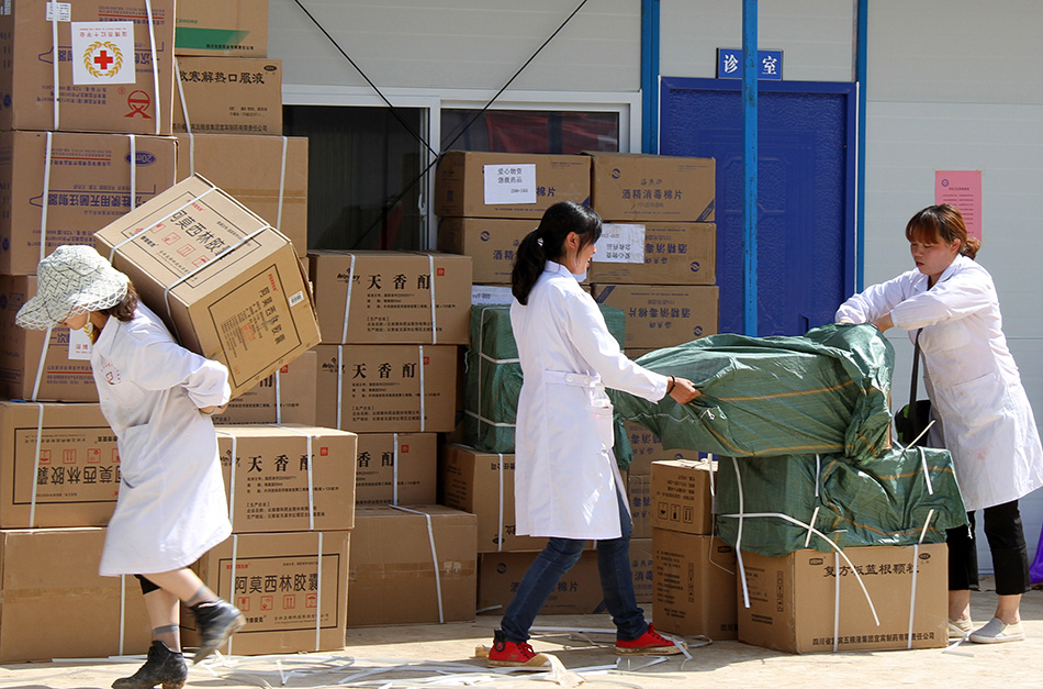 8月13日，龙头山镇中心卫生院的医护人员在板房医院内搬运药品，为接诊做准备。