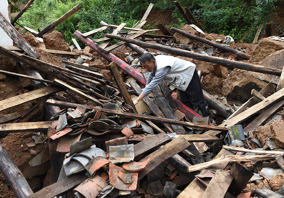 8月13日，谢维礼老人在自家被震毁的废墟内寻找可用的物品。