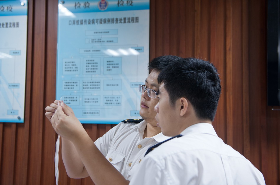  8月13日，深圳市出入境检验检疫局福田口岸旅检处工作人员查看发热旅客的检验样本。