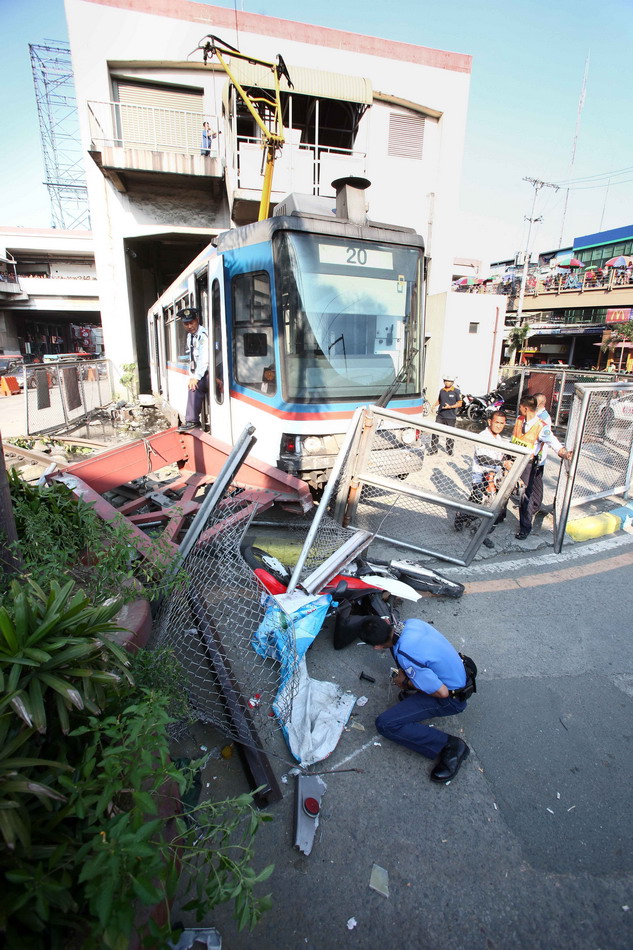  8月13日，在菲律宾帕赛市，一名警察查看城铁脱轨事故现场的一辆摩托车。