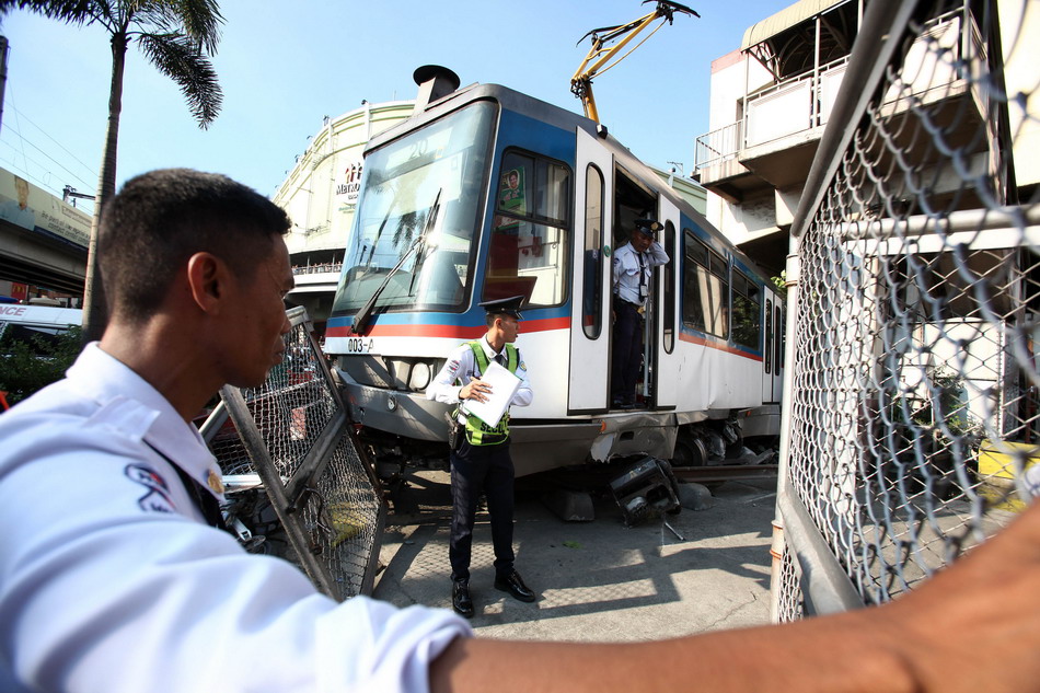  8月13日，在菲律宾帕赛市，安保人员在脱轨城铁车厢附近维持秩序。