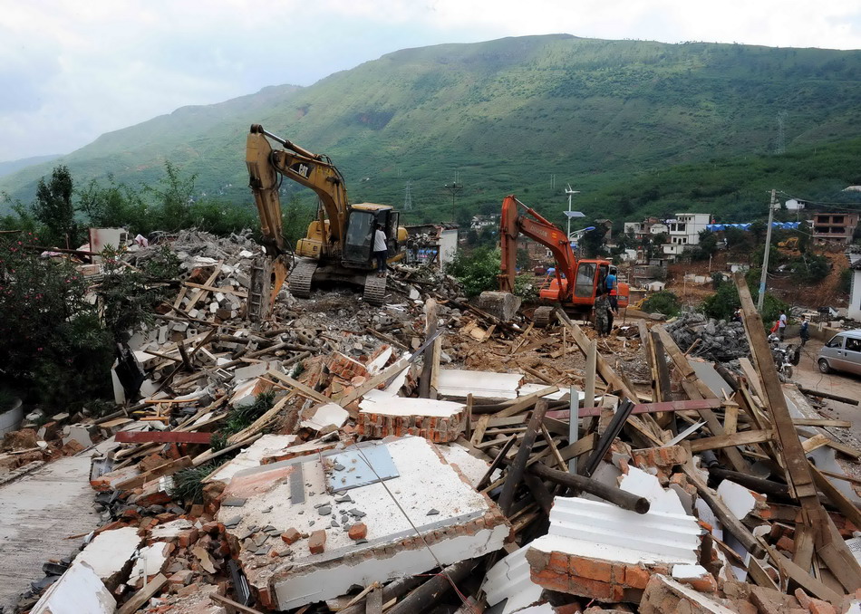  8月19日，两台挖掘机在鲁甸地震震中龙头山镇骡马口村为灾民清理废墟。