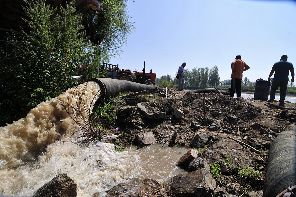 8月20日，在牡丹江市西安区海南乡河夹村，人们使用大型灌溉设备向灌渠排水。