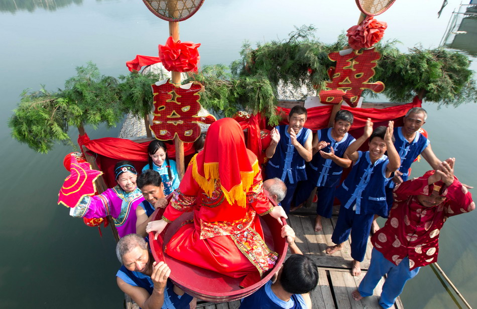  8月24日，在浙江省建德市梅城镇三江口村新安江上，参加“九姓渔民水上婚礼”的渔民用渔盆抬起“新娘”。