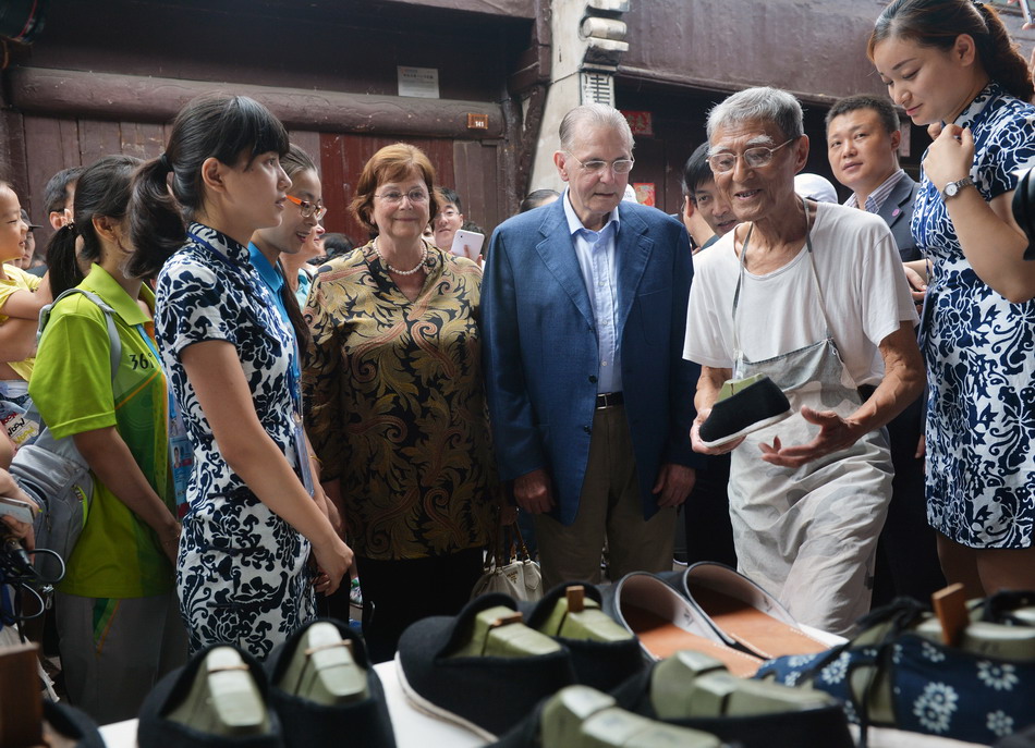  8月24日，国际奥委会名誉主席罗格在高淳老街梅家鞋铺前参观。86岁的店主梅位炳，纳鞋已有73年。他向罗格夫妇一人赠送了一双亲手做的布鞋。