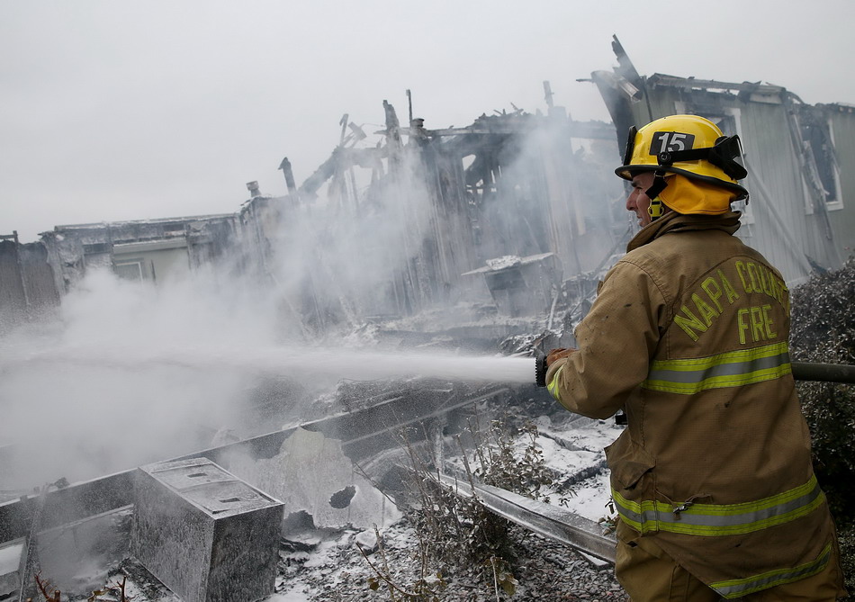  8月24日，在美国纳帕地区，一名消防员向一处因地震引发火灾的区域喷洒泡沫。新华社/法新