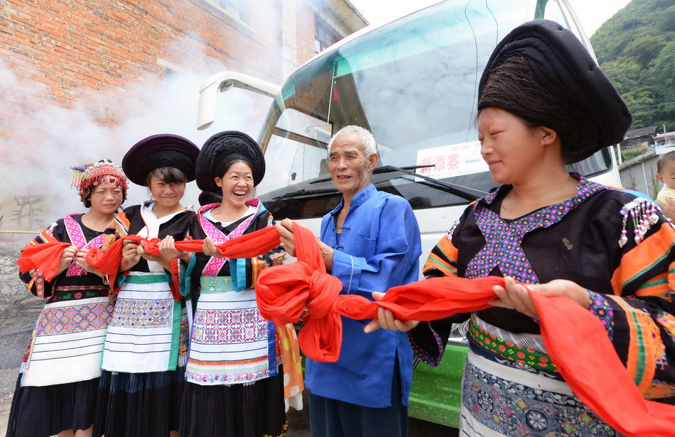 8月25日，在贵阳市乌当区下坝镇谷金苗族村，76岁的夏天国老人（右二）为谷金苗族村中巴客运发车剪彩。