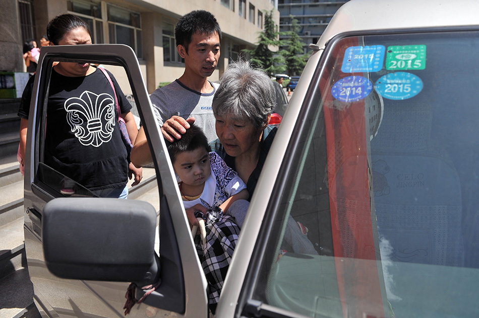 8月25日，在太原市山西省儿童医院，小可然在父亲、奶奶的陪伴下坐上回家的汽车。陈博源摄