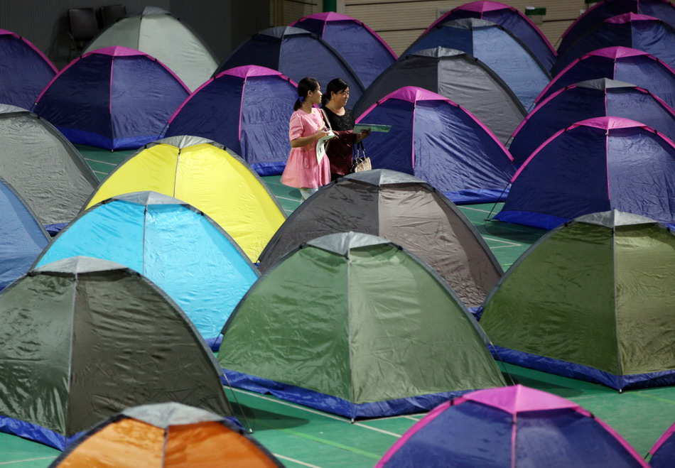 9月3日晚，一对母女从天津大学体育馆“爱心帐篷”中间走过。新华社发（刘东岳 摄）