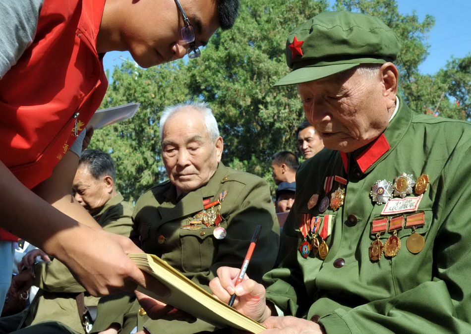  9月3日，在庆祝抗战胜利69周年暨甘肃抗战纪念馆开馆仪式上，一名抗战老兵在为青年志愿者签名。