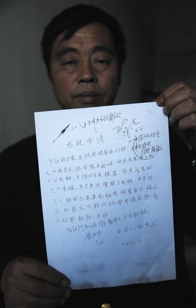 10月15日，北京，安徽宿州人黄新民拿着《求救申请》。申请落款是他爱人徐思兰签的名。 新京报记者 尹亚飞 摄