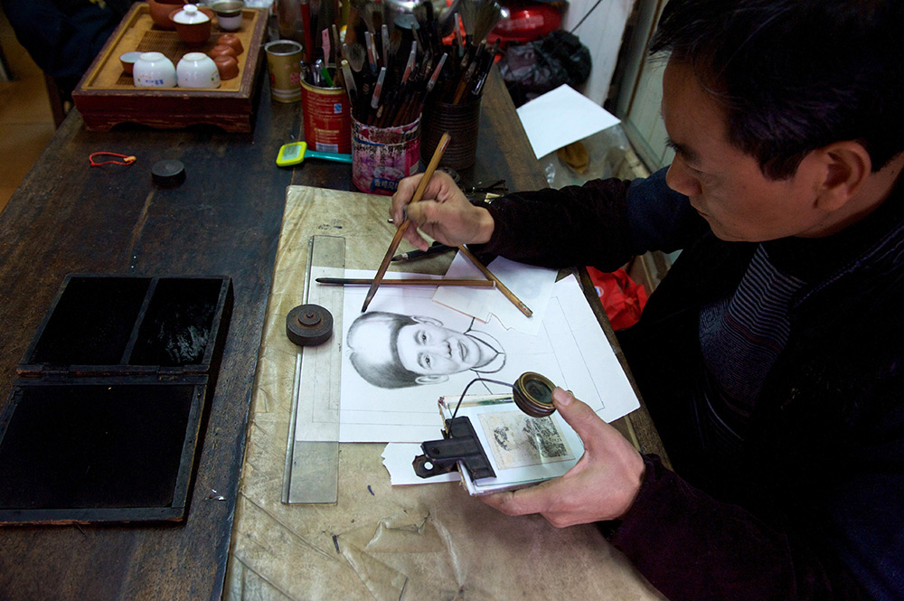 2015年1月30日，在漳州老街延安南路142号 “松年画像”店 ，52岁的陈松年正在参照破损的老照片画像。他从父亲那里继承了炭画民间绘画艺术。新华社记者 姜克红 摄