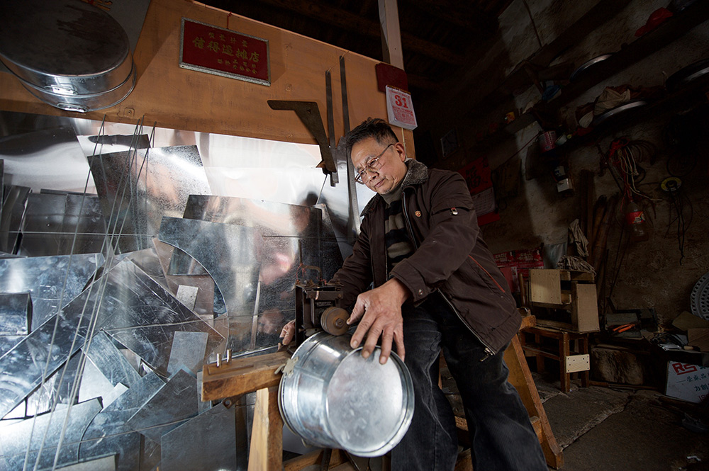 2015年1月31日，在漳州老街延安南路162号“广茂记白铁行”店，70岁的李伟茂在制作铁桶。李伟茂向父亲学会手工制作铁具，与妻子一起经营白铁行。新华社记者 姜克红 摄