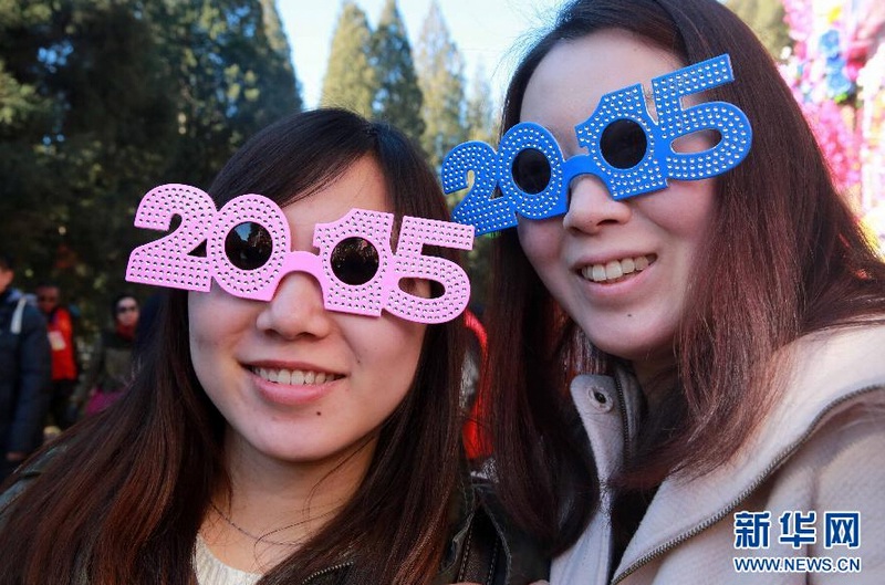  2月18日，两个女孩戴着“2105”字样的眼镜开心逛庙会。 新华社发（陈晓根 摄）