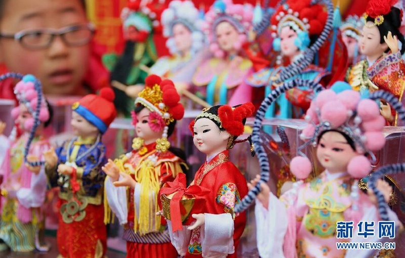 2月19日，一名小朋友在北京通州区“运河文化庙会”上欣赏“绢花”工艺品。当日是羊年大年初一，北京大观园红楼庙会、地坛庙会、运河文化庙会、八大处新春祈福庙会、石景山“洋庙会”等庙会同时拉开帷幕，将丰富多彩的文艺节目和民俗展演送到市民和游客的身边。新华社发（卜向东 摄）