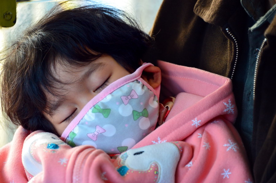 在济南市34路公交车上，一位小朋友躺在爷爷怀里睡觉（3月19日摄）。 