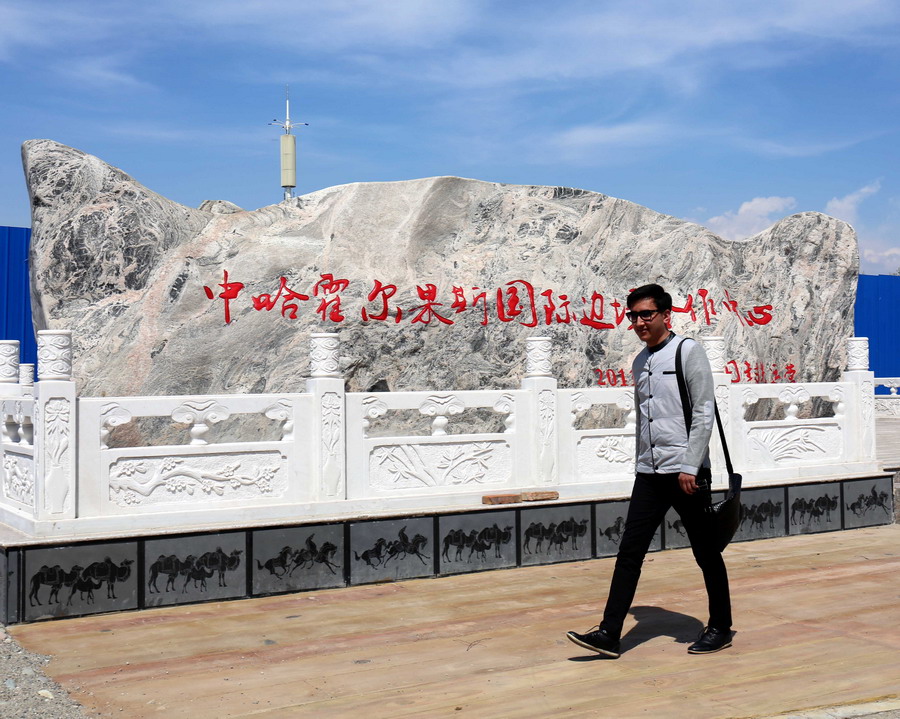 4月30日，一名男子走过中国哈萨克斯坦霍尔果斯国际边境合作中心中方一侧的地标。新华社记者 周良 摄