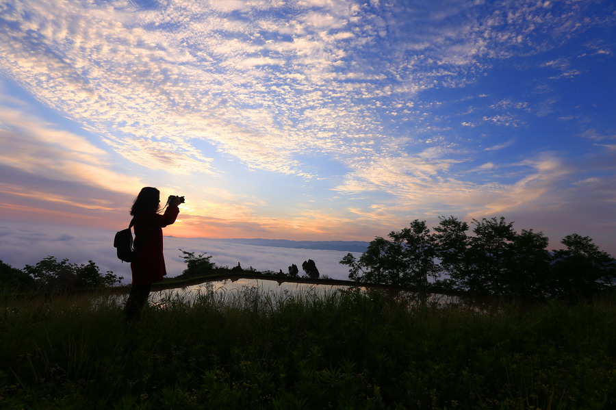 5月19日，一名游客在贵州凯里雷公山脉小高山拍摄云海朝霞。新华社发（吴吉斌 摄）