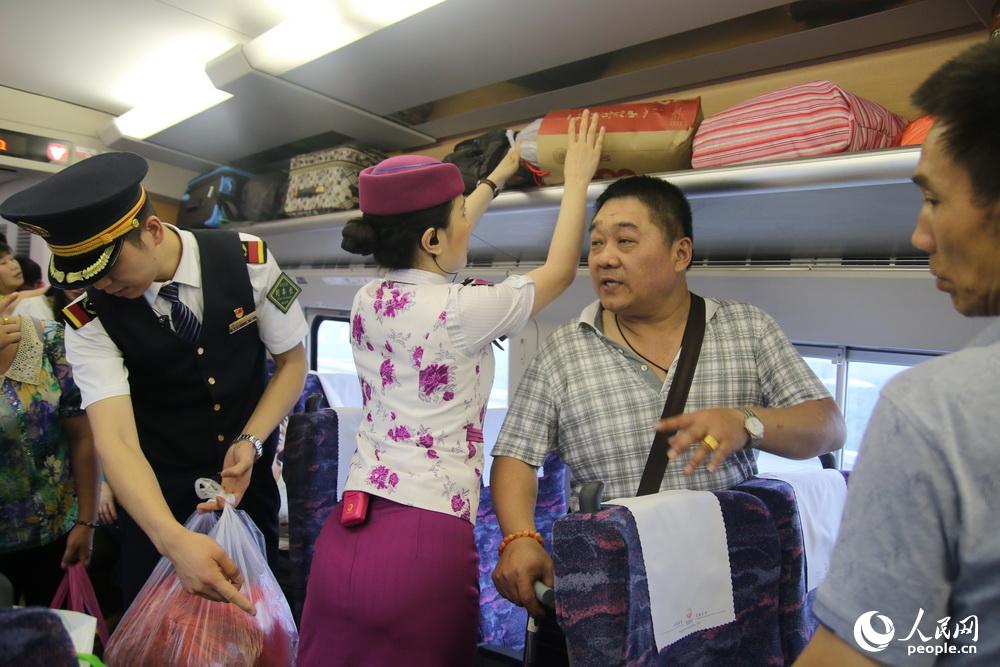 陈鑫和动妹帮助旅客把行李包放到行李架上。