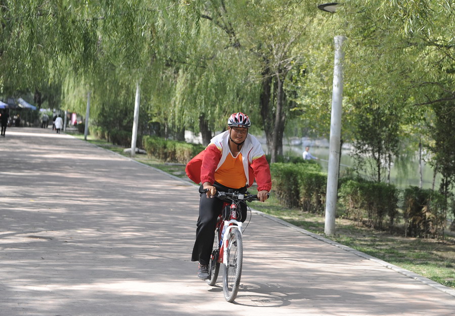 图为铁钢在呼和浩特市青城公园内骑车锻炼腿部力量。（2014年9月17日摄）新华社记者 邵琨 摄