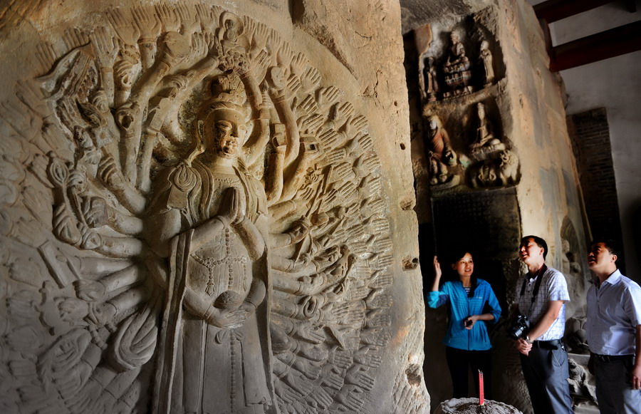 5月20日，游人在参观钟山石窟前壁上的明代“千手观音”。新华社记者 陶明 摄