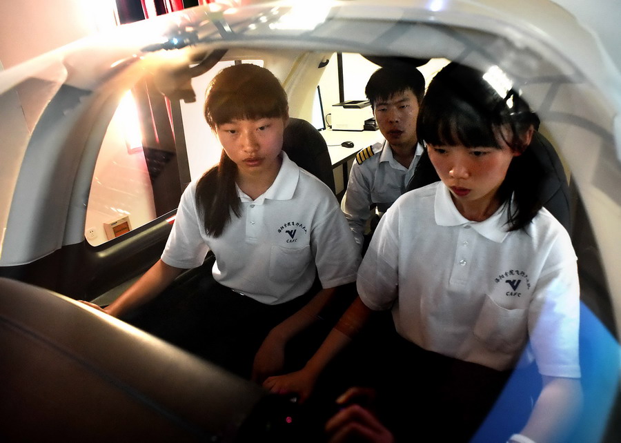 照(前右)在教练的指导下操作模拟飞行训练器。