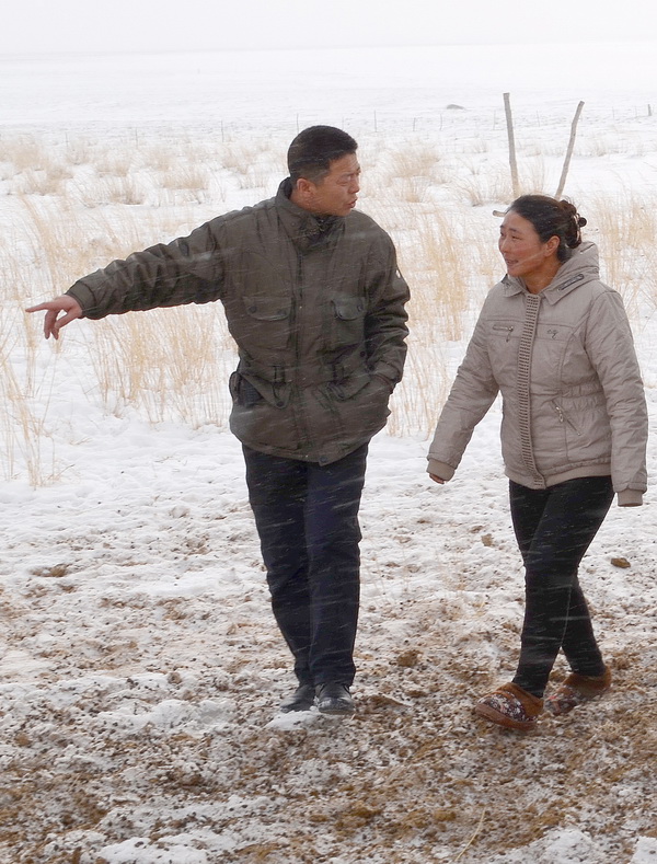 吉日嘎拉（左）冒着风雪了解牧户家情况（2013年12月25日摄）。