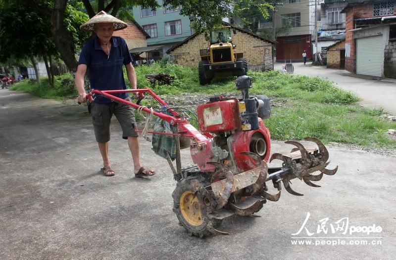 6月22日，在广西柳州市融水苗族自治县融水镇西洞村，一名村民开着整耕机去田劳作。