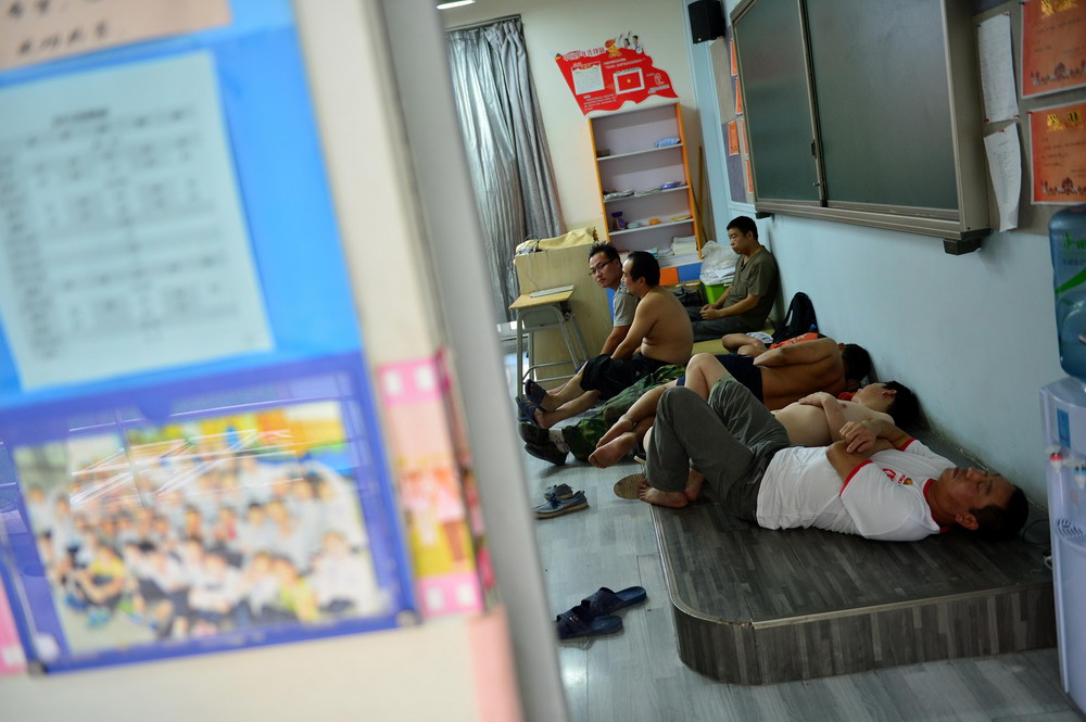 8月13日，周边居民在天津开发区第二小学教室里休息。 