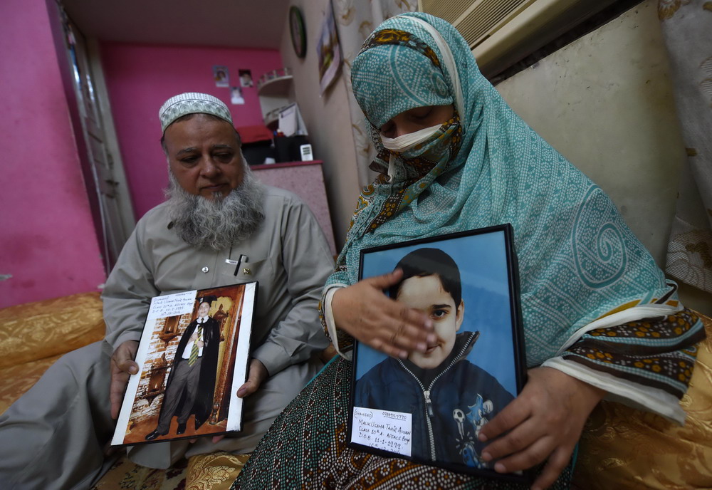 8月13日，在巴基斯坦白沙瓦，一对父母手捧在去年12月军人子弟学校袭击事件中遇难的儿子的照片。
